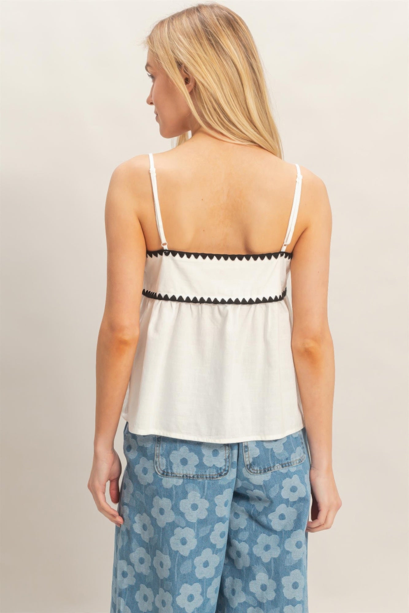Dos du haut babydoll blanc sans manches, bordure noire et bretelles fines.