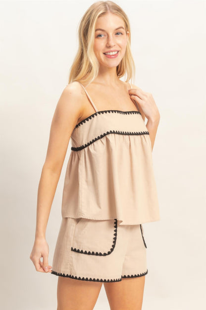 Haut babydoll beige sans manches, bretelles fines et bordure noire avec volants.
