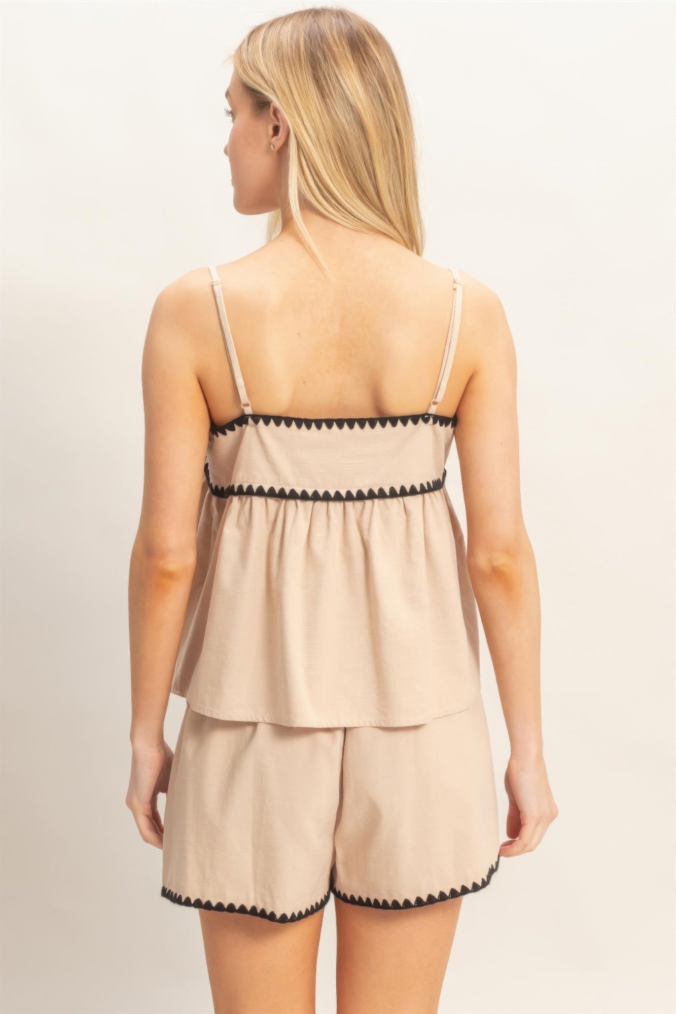 Débardeur babydoll beige à bretelles fines, volants courts, bordure zigzag contrastée.