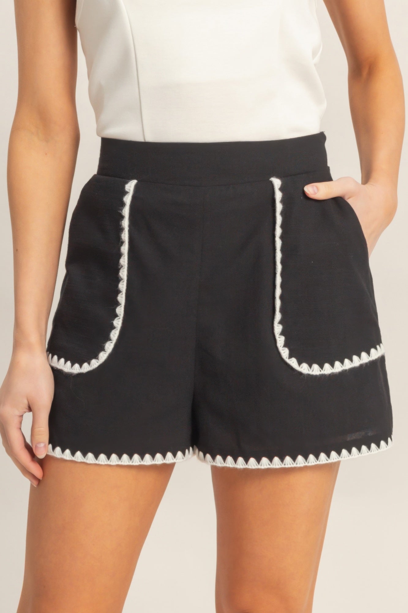 Shorts taille haute noirs à bordure festonnée blanche sur poches