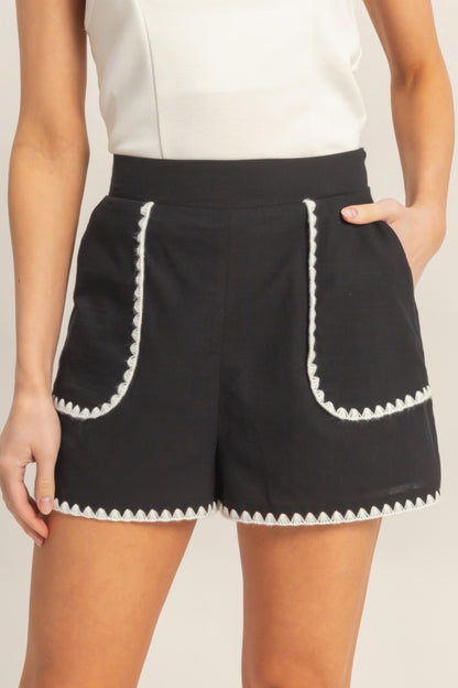 Shorts taille haute noirs à bordure festonnée blanche sur poches