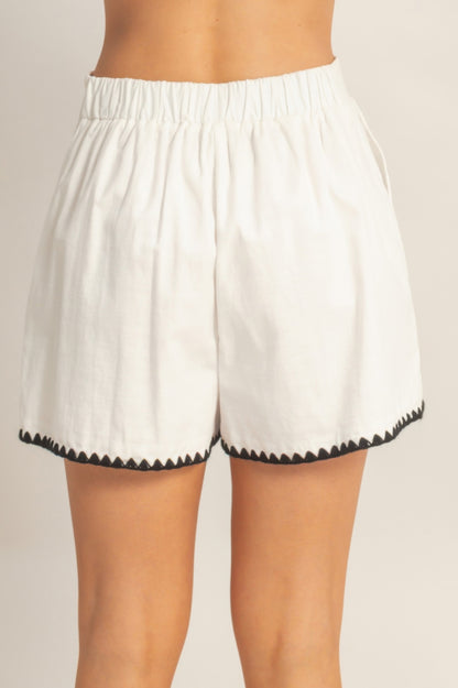 Shorts taille haute blancs à taille élastique et bord festonné noir