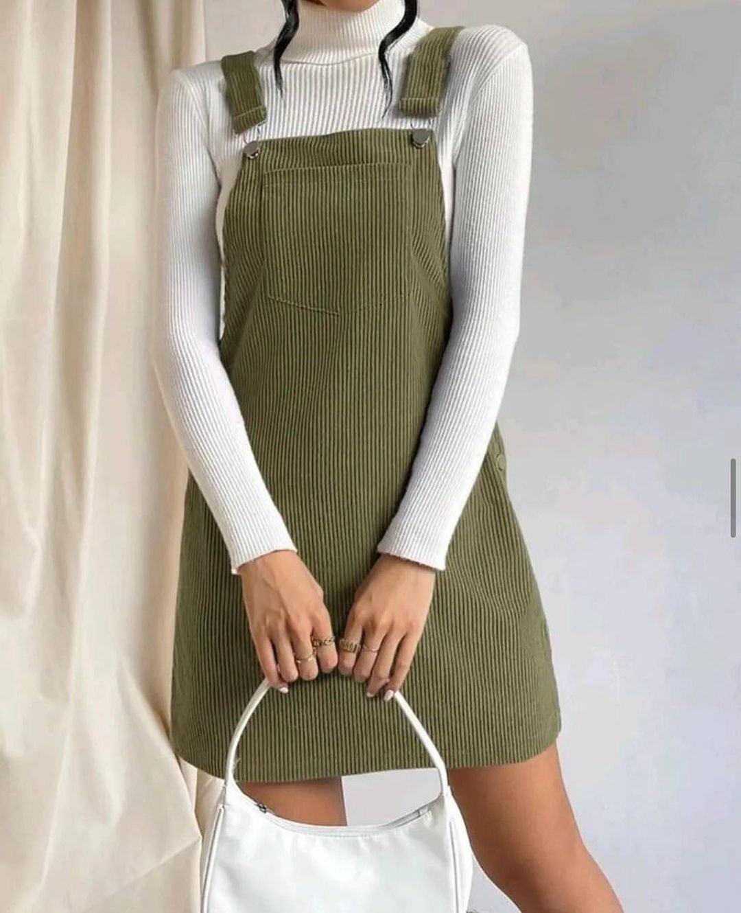 Robe sans manches en velours côtelé kaki foncé, bretelles boutonnées, poche centrale.