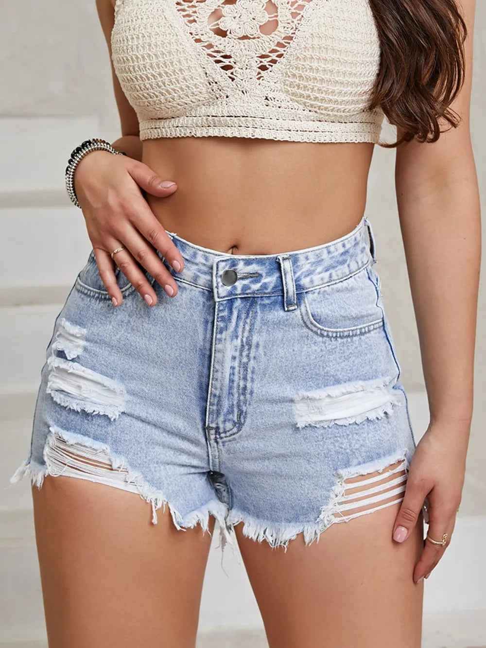 Short taille haute en jean bleu ciel usé, déchirures sur les jambes, franges