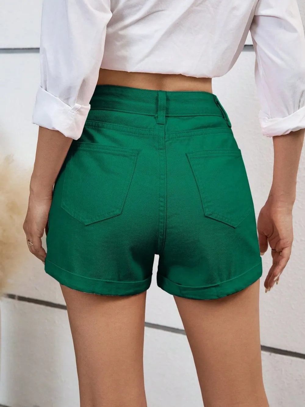 Short taille haute vert avec poches arrière et fermeture boutonnée.