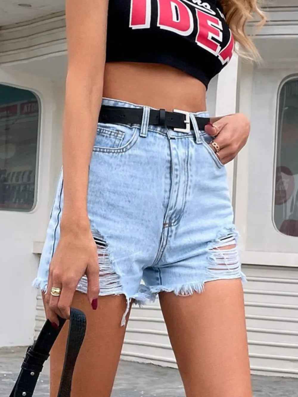 Short en jean bleu clair taille ceinturée, fermeture boutonnée, déchirures sur la jambe, ourlet