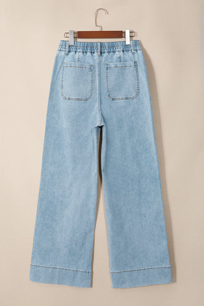 Jean en denim bleu ciel, taille élastiquée, jambe ample, poches avant visibles.