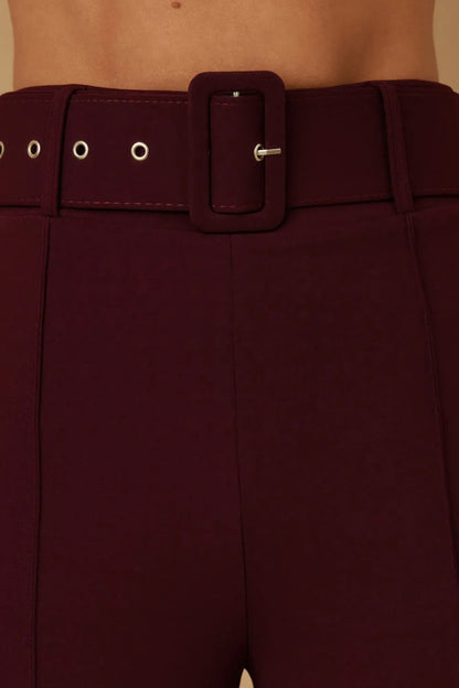Détail pantalon bordeaux : ceinture à boucle carrée et œillets sur le passants