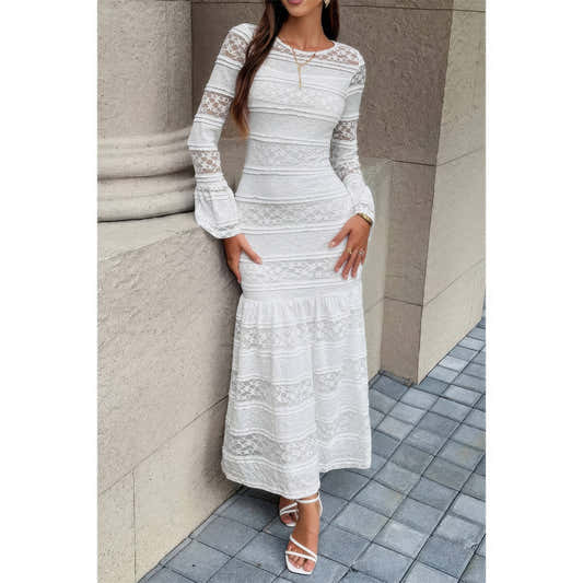 Robe longue en dentelle blanche à encolure ronde, manches longues et ourlet volanté.