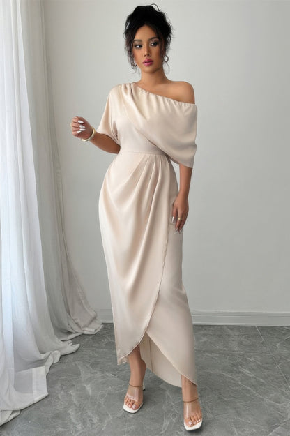 Robe asymétrique une épaule beige, manches courtes, drapé croisé et fente avant.