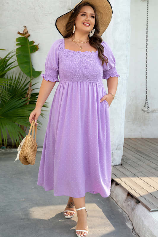Robe mi-longue lilas à pois discrets, manches bouffantes, buste froncé et ourlet volanté.
