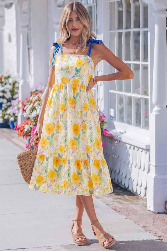Robe midi à bretelles fines, imprimé floral jaune, nœuds bleus sur les épaules.
