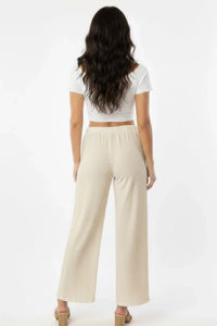 Pantalon large blanc cassé en coton, dos, taille élastique et jambe ample.