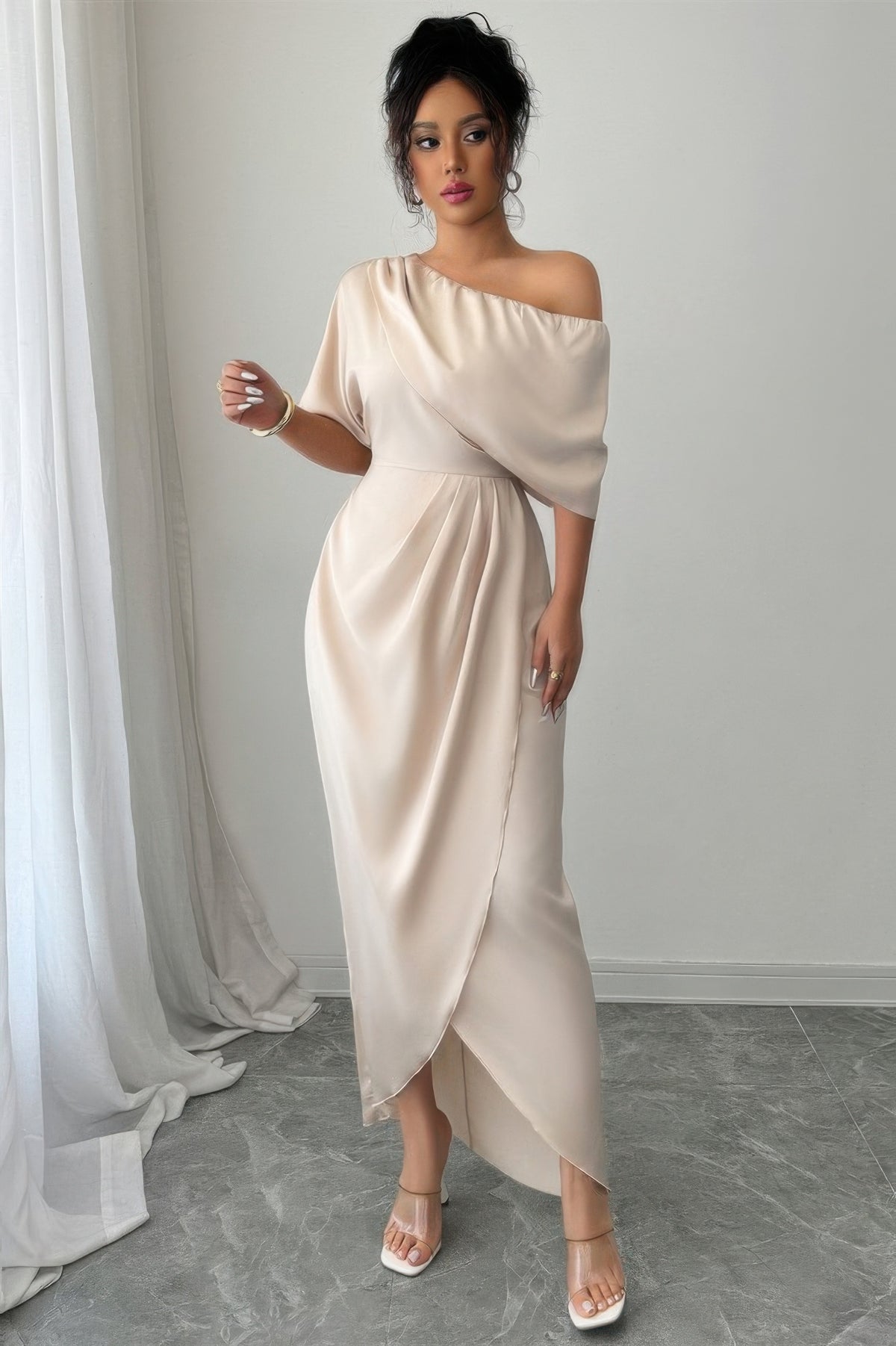 Robe asymétrique une épaule beige, manches courtes, drapé croisé et fente avant.