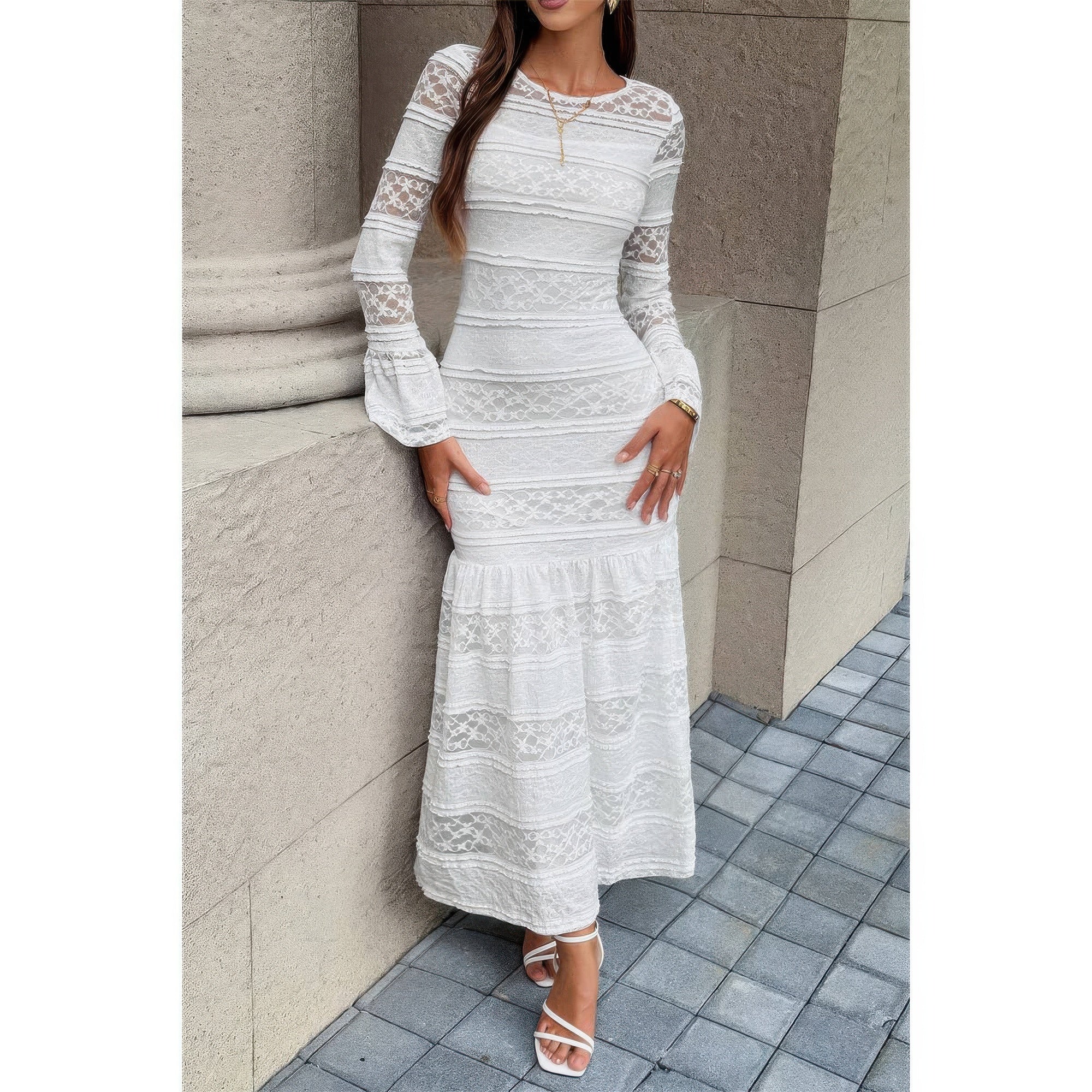 Robe longue en dentelle blanche à encolure ronde, manches longues et ourlet volanté.