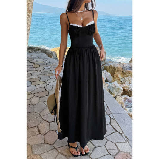 Robe longue noire à bretelles spaghetti, jupe ample froncée, bord dentelle blanche.