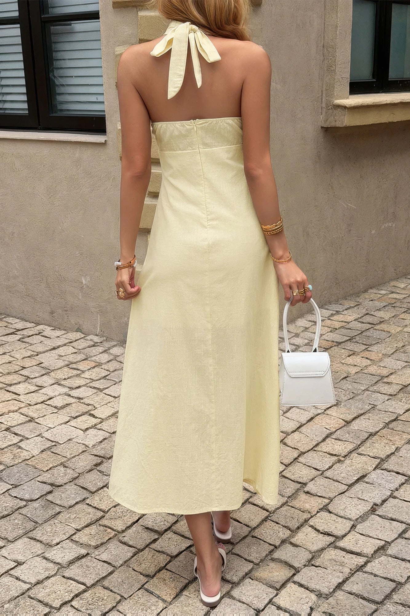 Robe longue jaune dos nu avec nœud au dos, bretelles halter, jupe évasée.