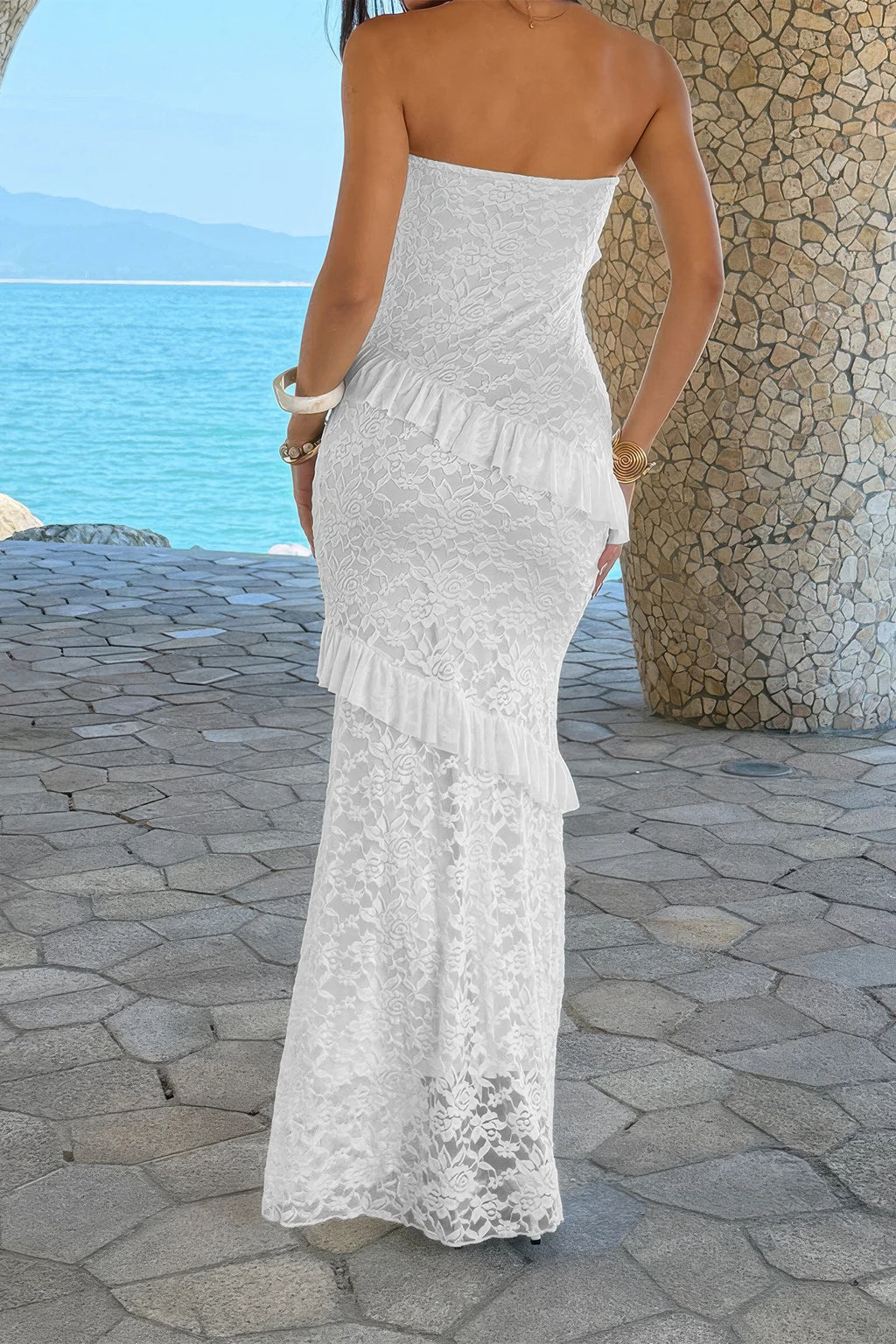 Robe longue en dentelle blanche, bustier sans bretelles et volants superposés.