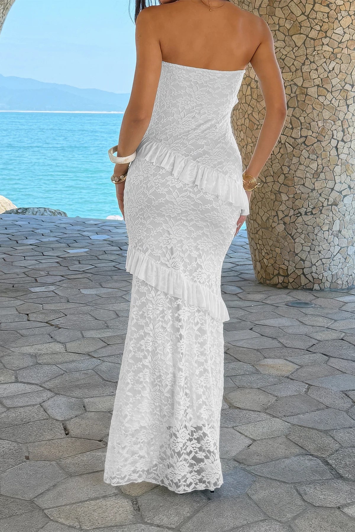 Robe longue en dentelle blanche, bustier sans bretelles et volants superposés.