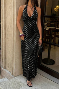 Robe longue sans manches noire à pois blancs, silhouette près du corps, encolure plongeante.