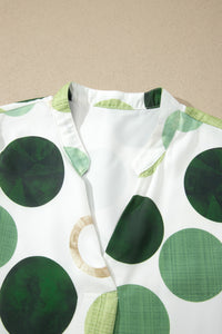 Robe blanche à pois verts, encolure en V avec revers et finitions plis