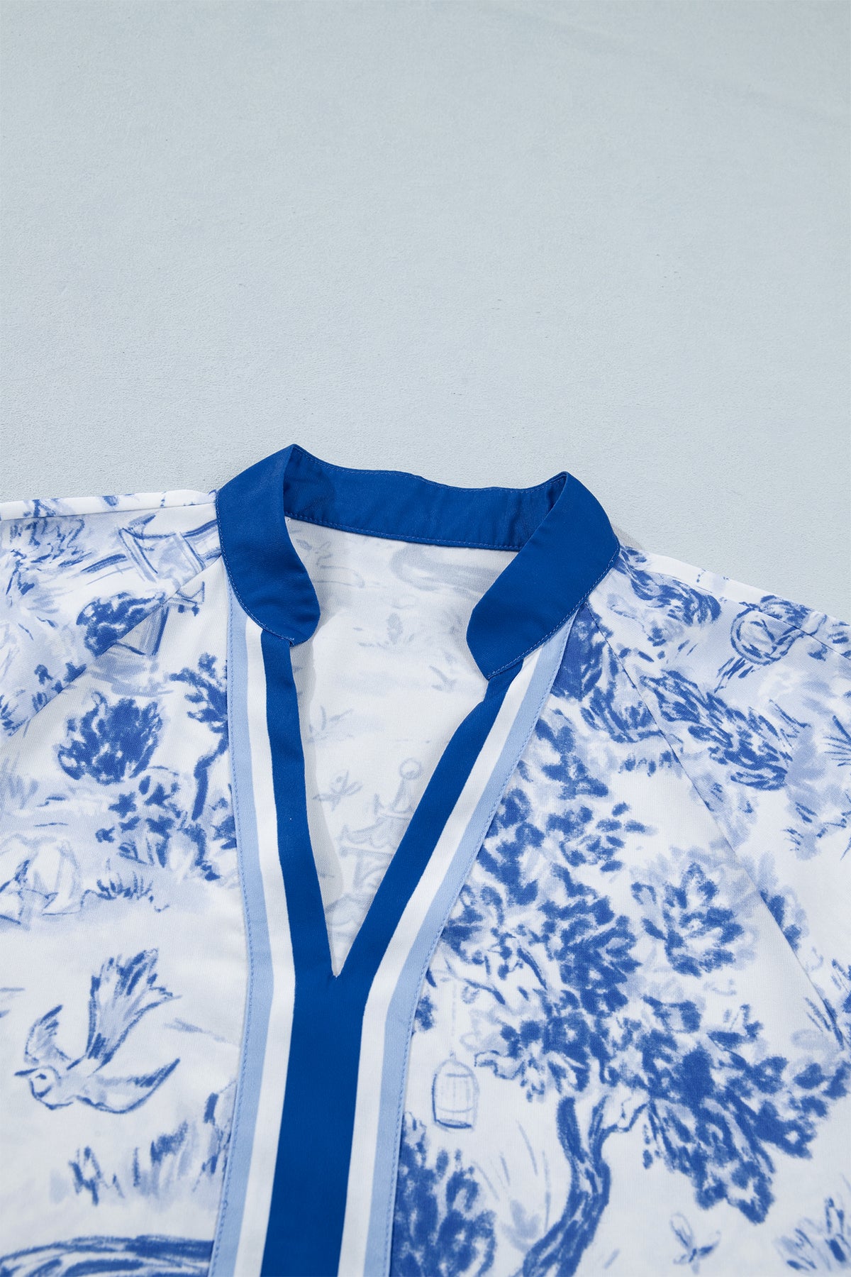 Haut femme col V contrasté bleu, bordure bleue et imprimé bleu sur fond clair.