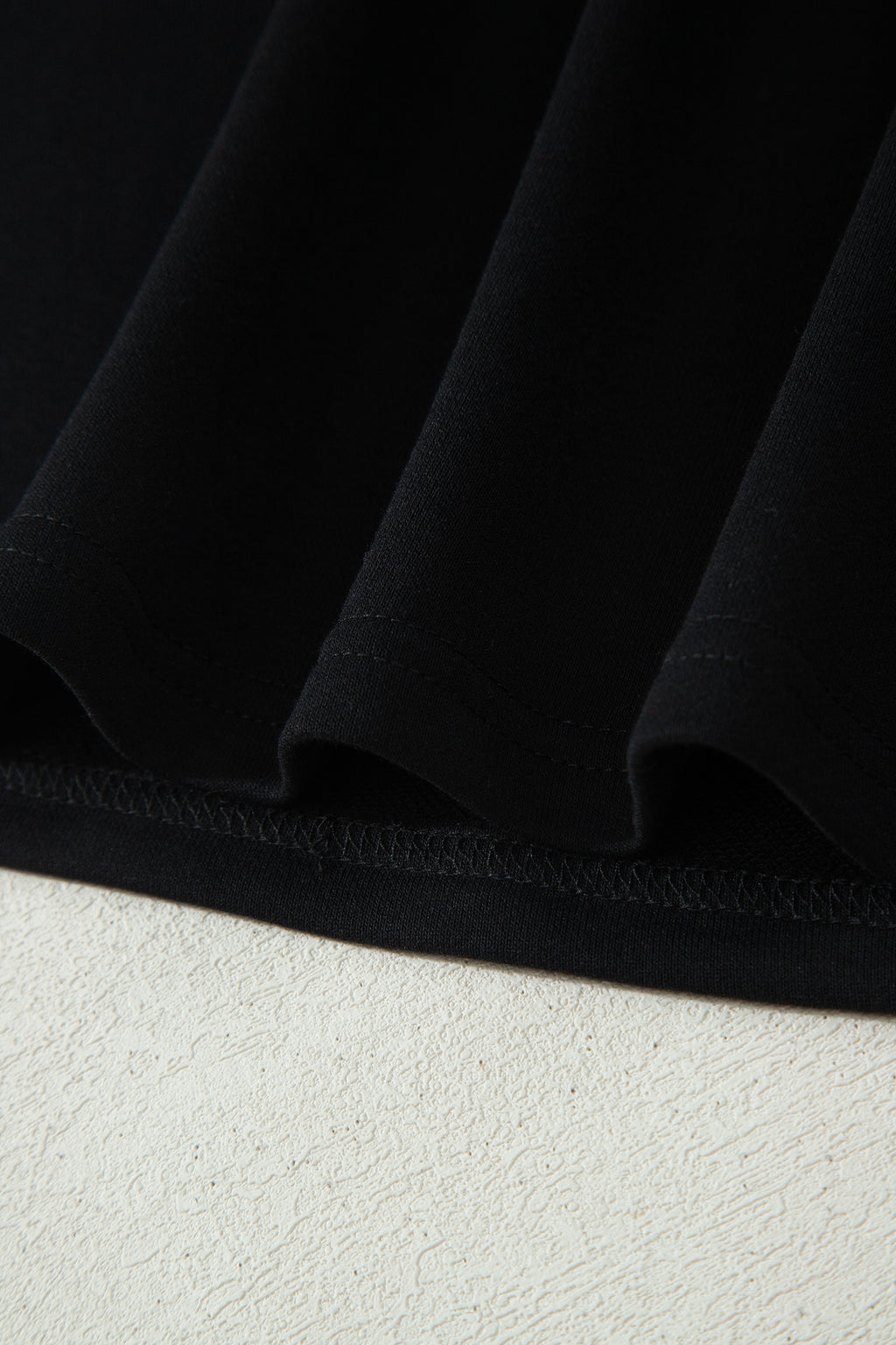 Haut polo bicolore en denim, ourlet bas noir et couture visible.