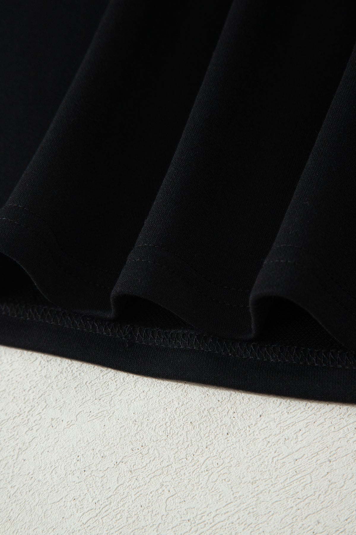 Haut polo bicolore en denim, ourlet bas noir et couture visible.