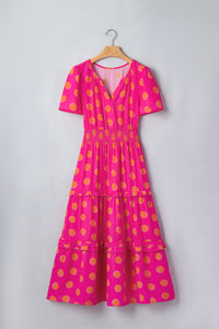Robe rose à pois jaune sur cintre, encolure V, manches courtes, volants étagés.
