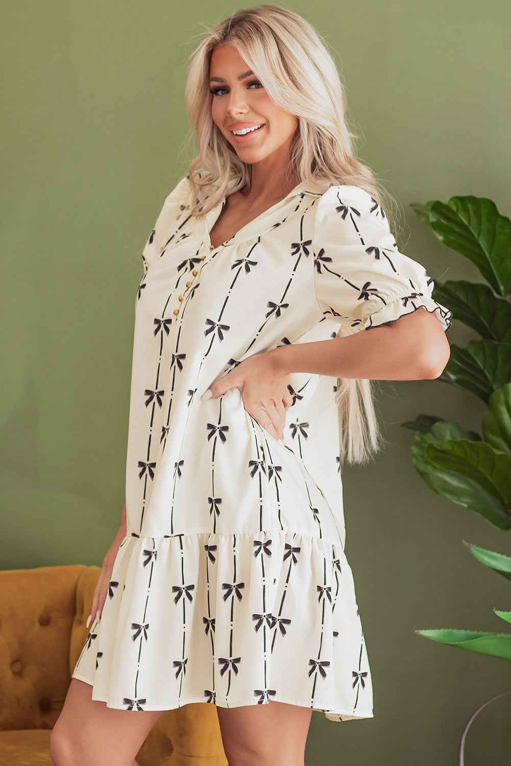 Robe courte crème à motifs nœuds papillon, col boutonné, volume à la taille.
