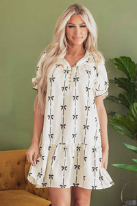 Robe courte crème à motifs nœuds papillon, col boutonné, jupe évasée.