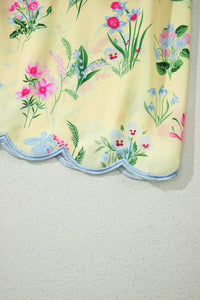 Ourlet festonné avec bordure bleu clair et fleurs multicolores sur robe crème.