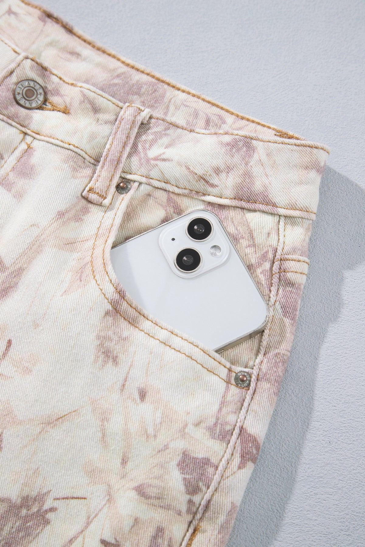 Jean large femme motif camouflage rose clair, bouton et fermeture à la taille.