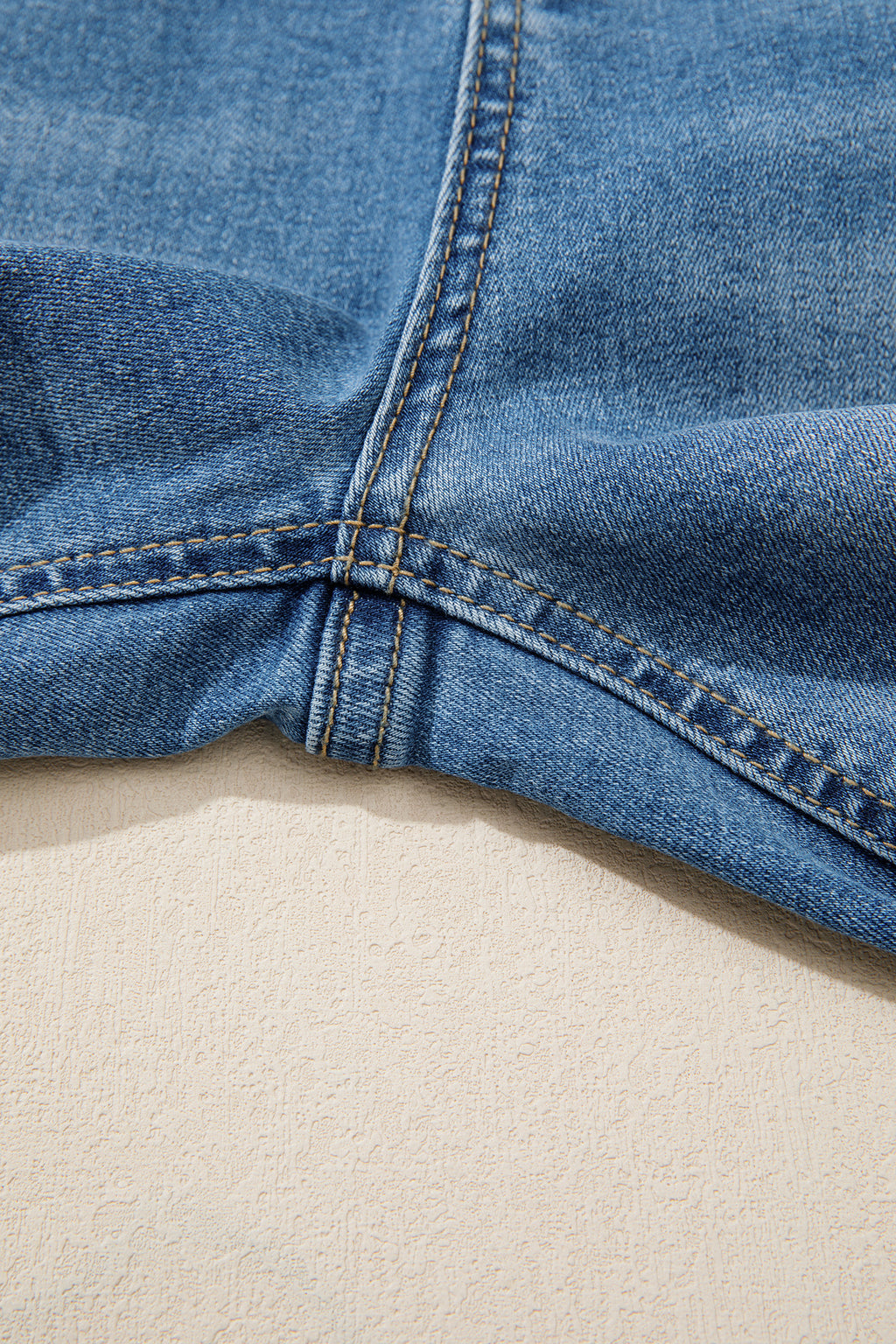 Ourlet de jean bleu myosotis, surpiqûres et couture intérieure visibles.
