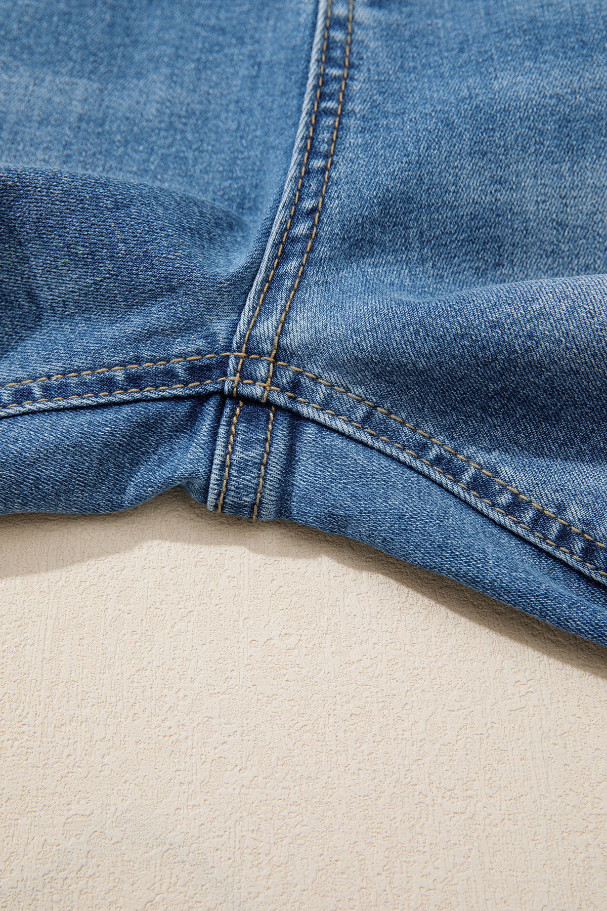 Ourlet de jean bleu myosotis, surpiqûres et couture intérieure visibles.