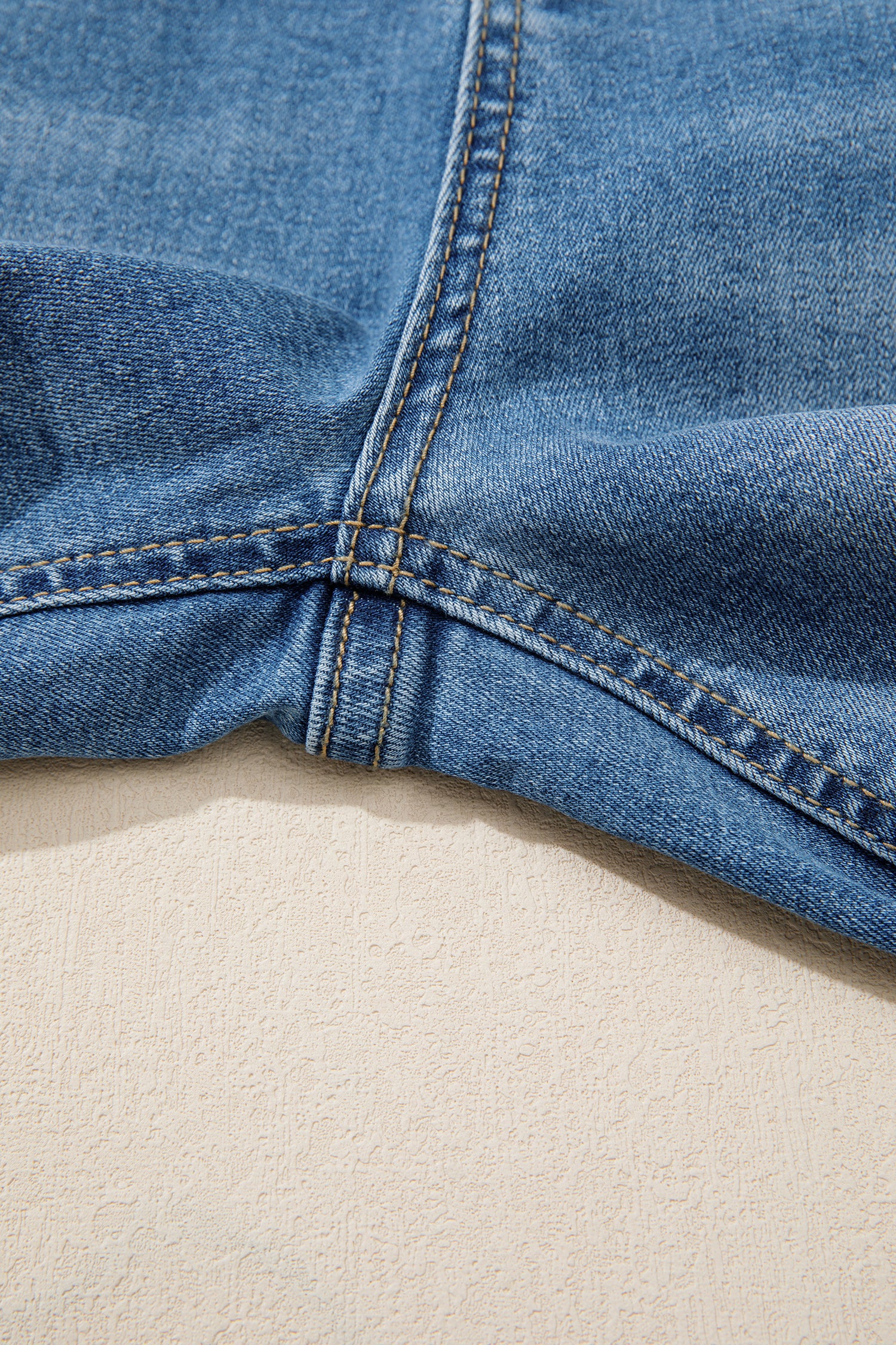 Ourlet de jean bleu myosotis, surpiqûres et couture intérieure visibles.