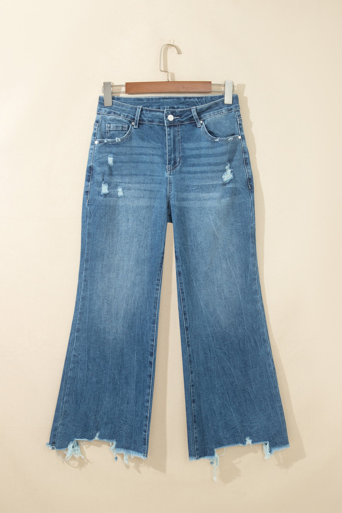 Jean flare taille haute bleu moyen, poches devant, ourlet effiloché et déchirures.
