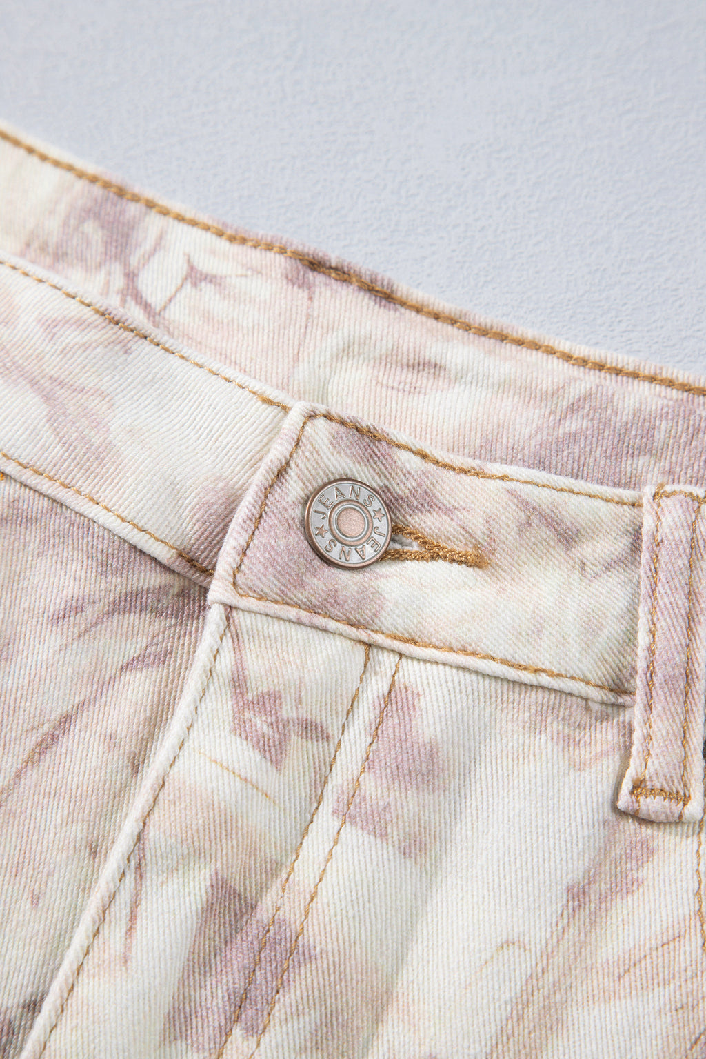 Jean large femme motif camouflage rose clair, gros plan sur la patte de bouton.