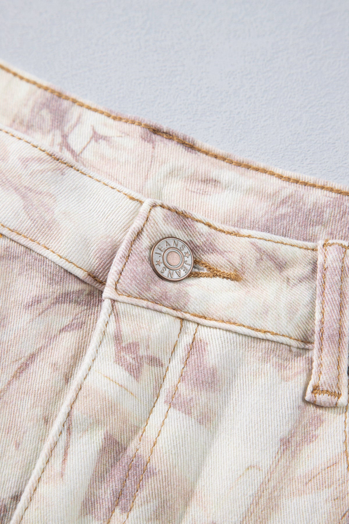 Jean large femme motif camouflage rose clair, gros plan sur la patte de bouton.