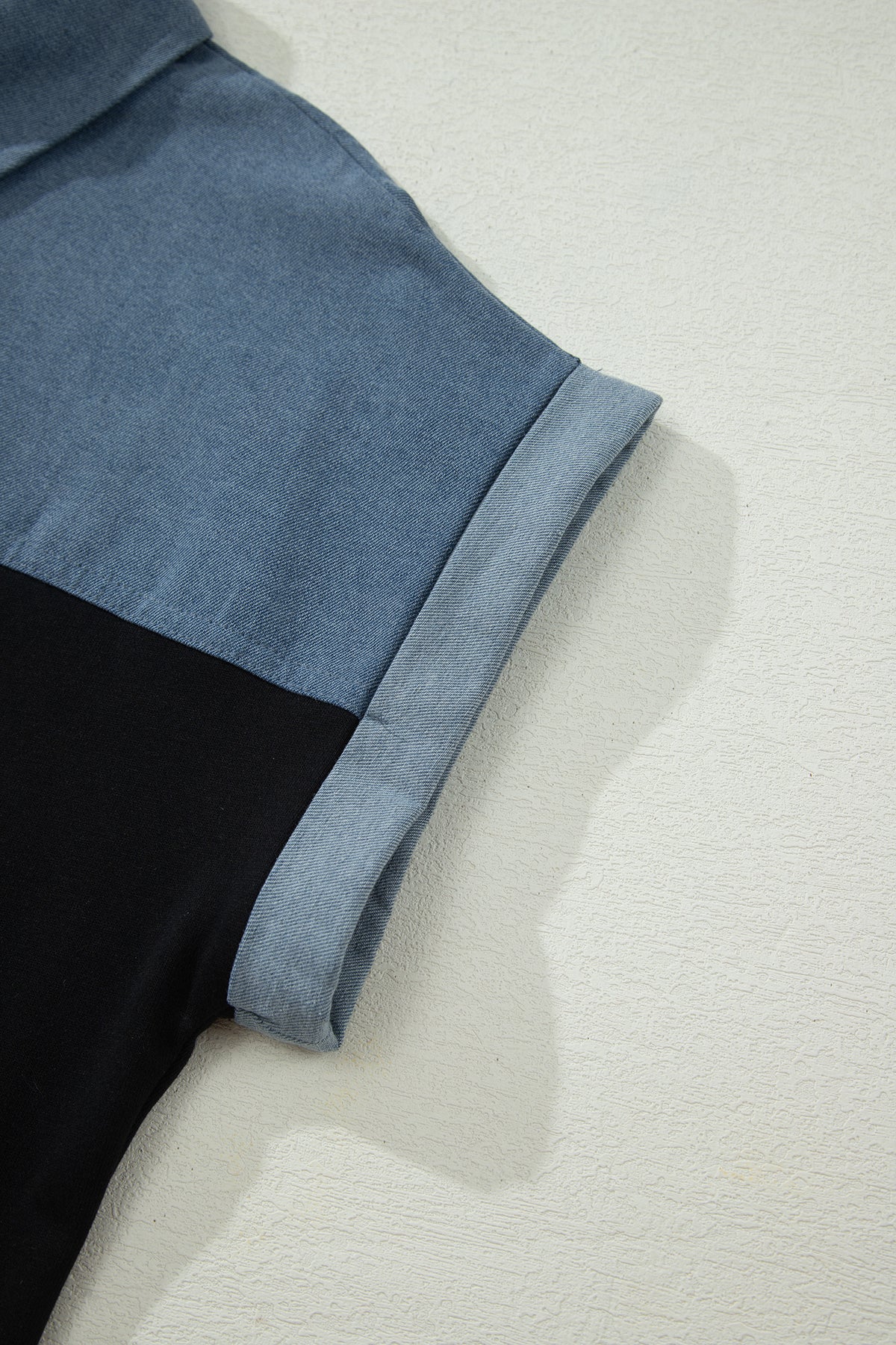 Haut polo bicolore en denim, détail manche et couture d’empiècement noir.