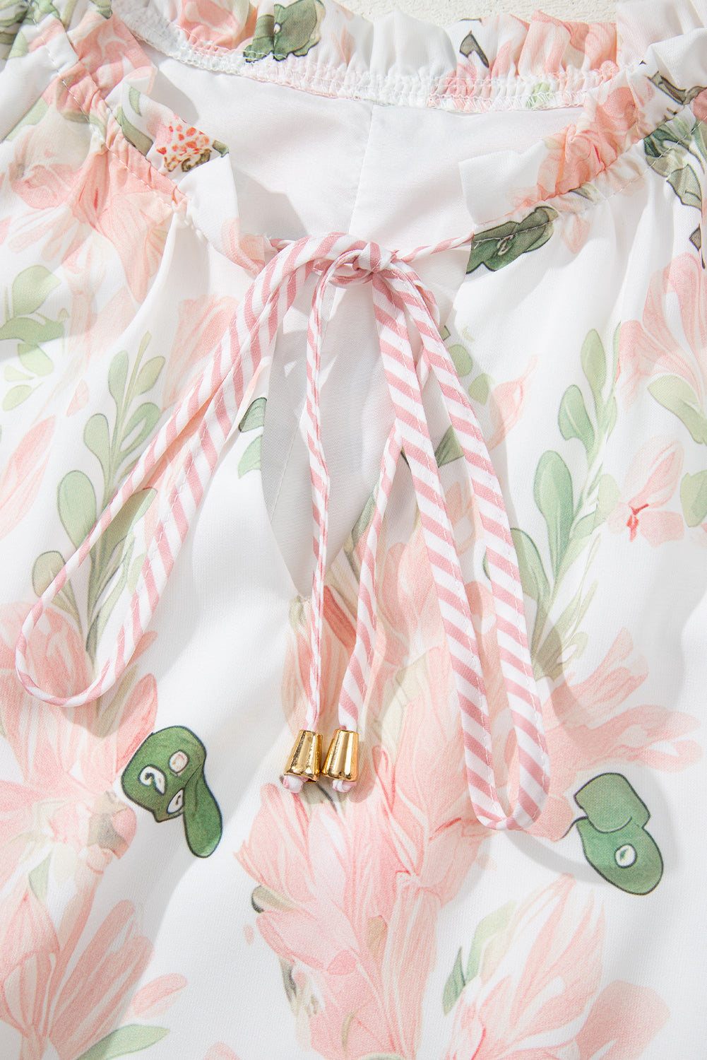 Robe courte rose à fleurs, nœud rayé avec extrémités dorées et rubans pendants.