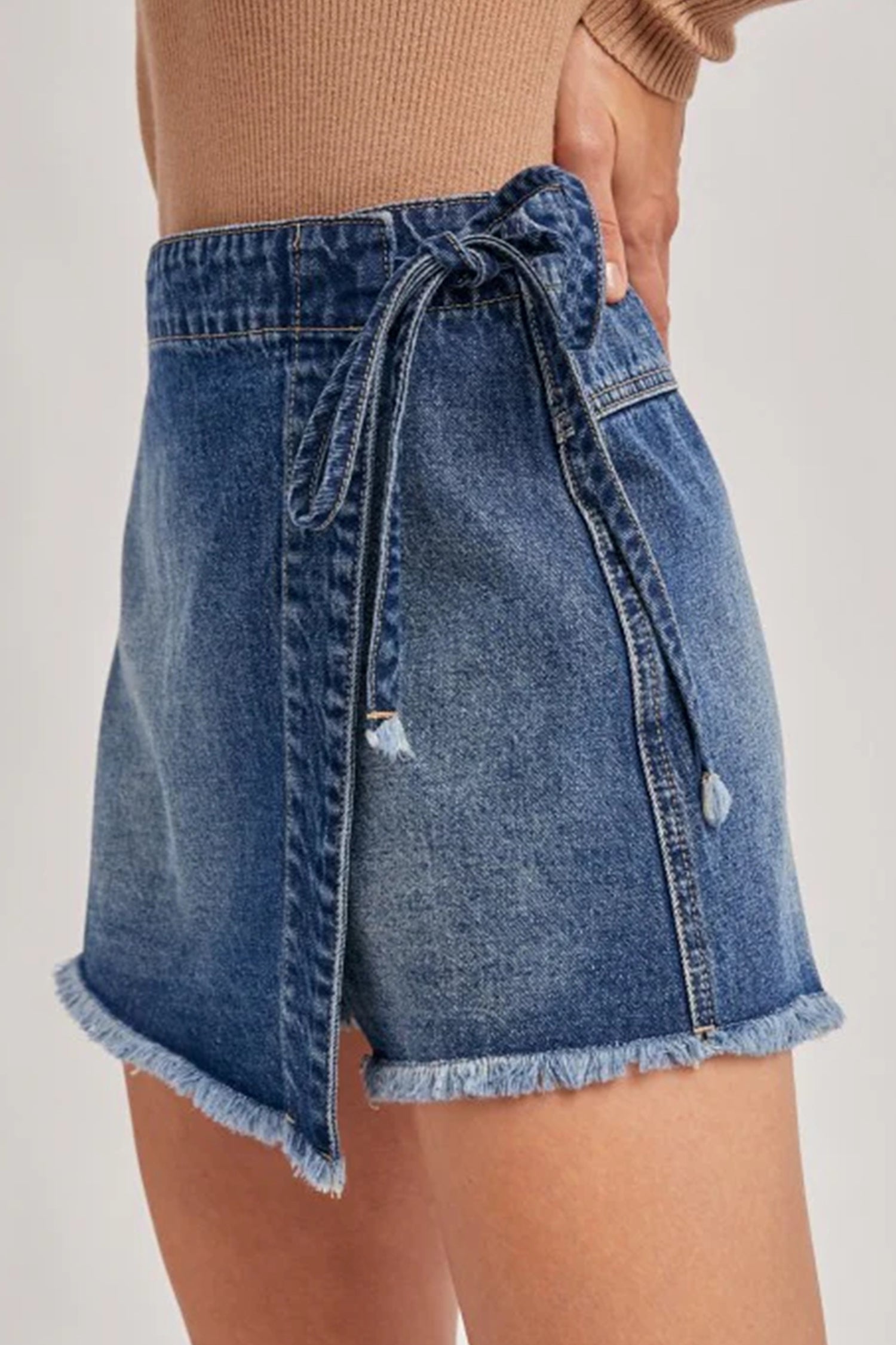 Short en jean bleu à ceinture nouée et poches à rabat, ourlet effiloché
