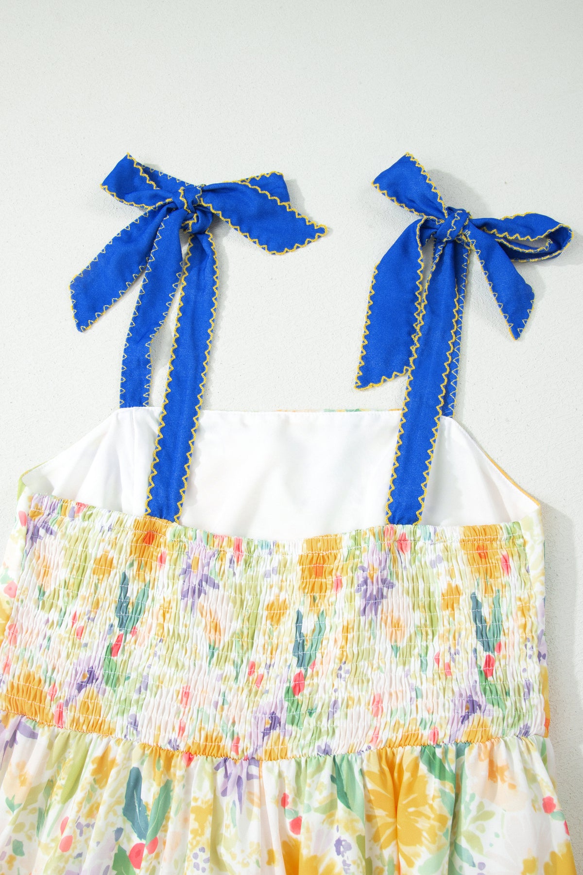 Haut de robe imprimé floral jaune, bretelles à nœuds bleus, fronces et volant.