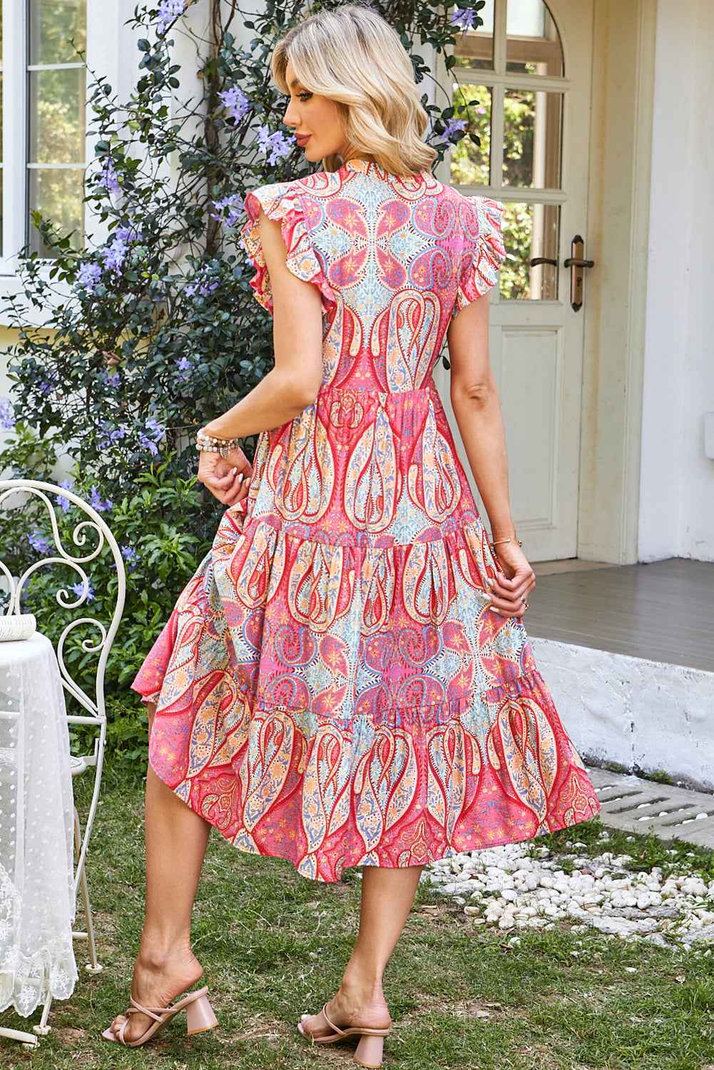 Robe mi-longue rose motif paisley, manches volantées, jupe évasée à volants.