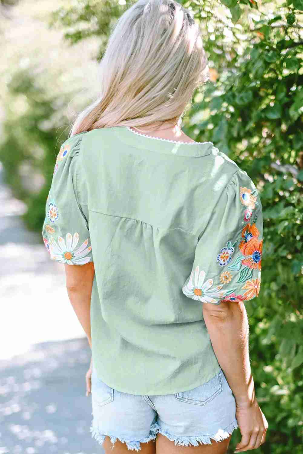 Chemisier femme vert clair à broderies florales multicolores, manches bouffantes.