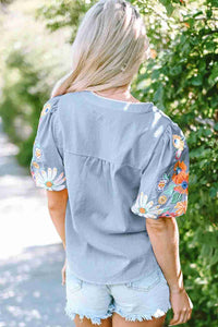 Chemisier femme gris à broderies florales multicolores au dos, manches courtes bouffantes.