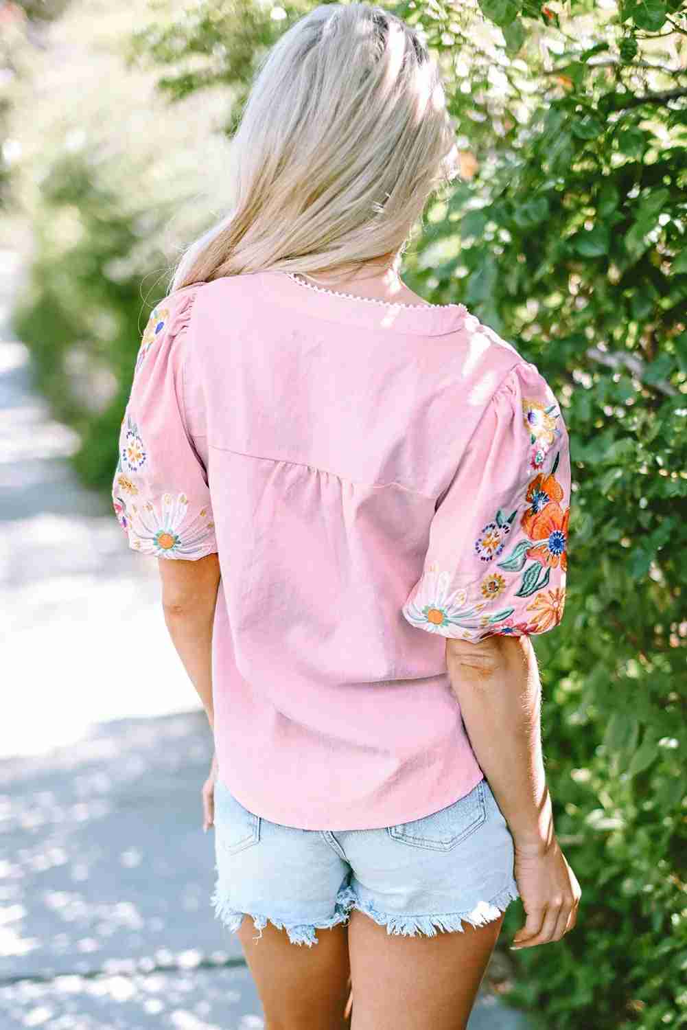 Chemisier femme rose à broderies florales multicolores au dos, manches bouffantes.