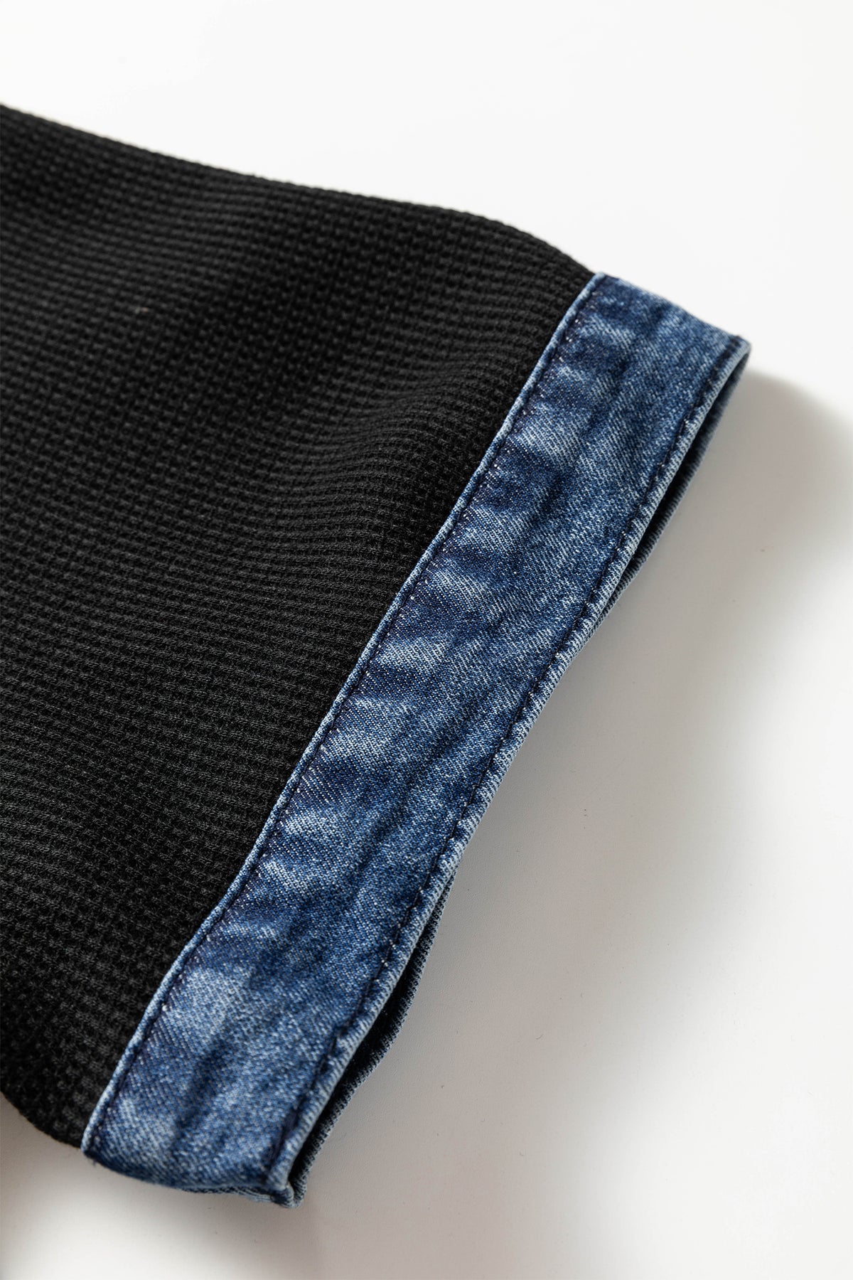 Bordure en denim bleu sur manche de robe noire.