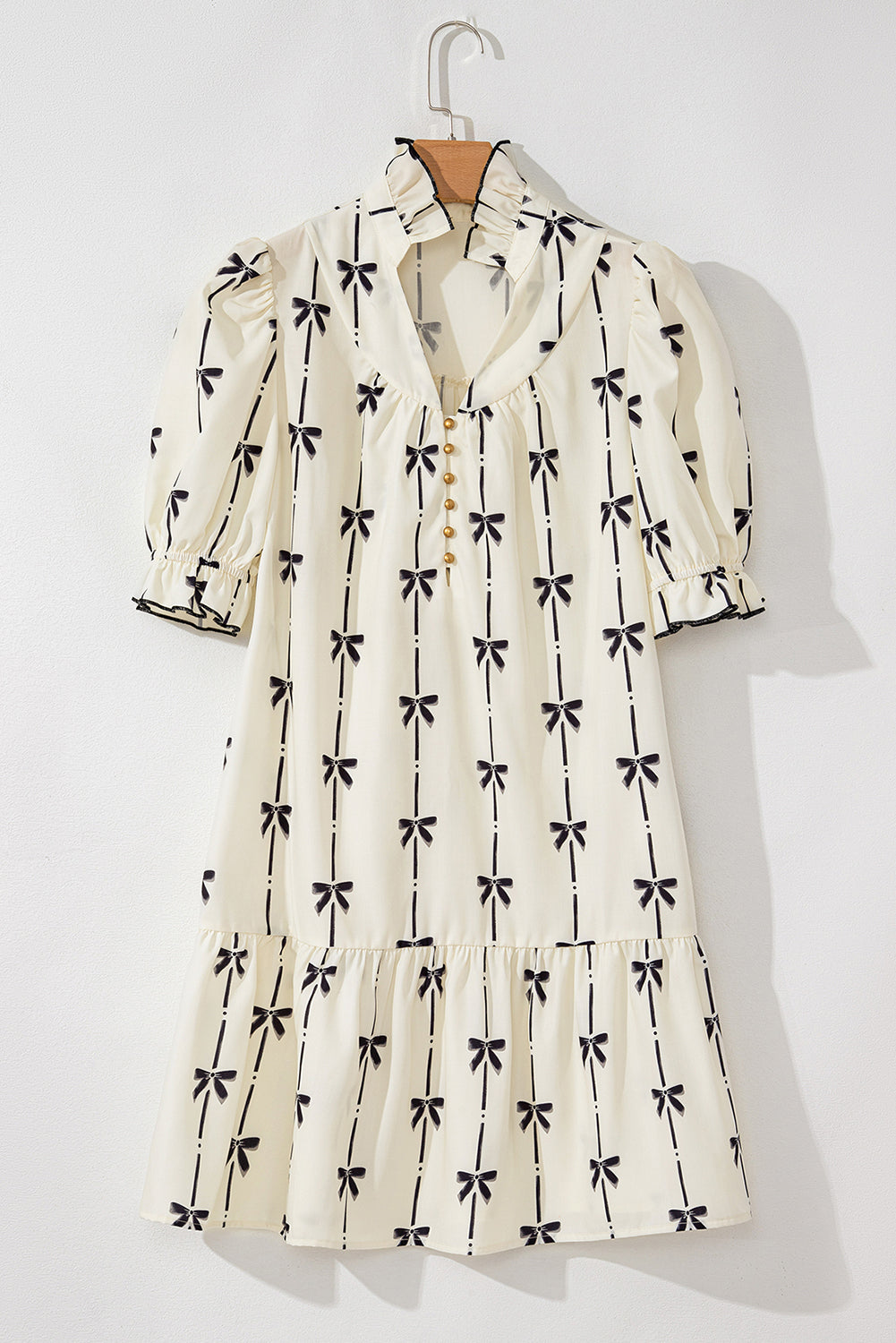 Robe courte sur cintre, crème à motifs nœuds papillon, manches bouffantes.