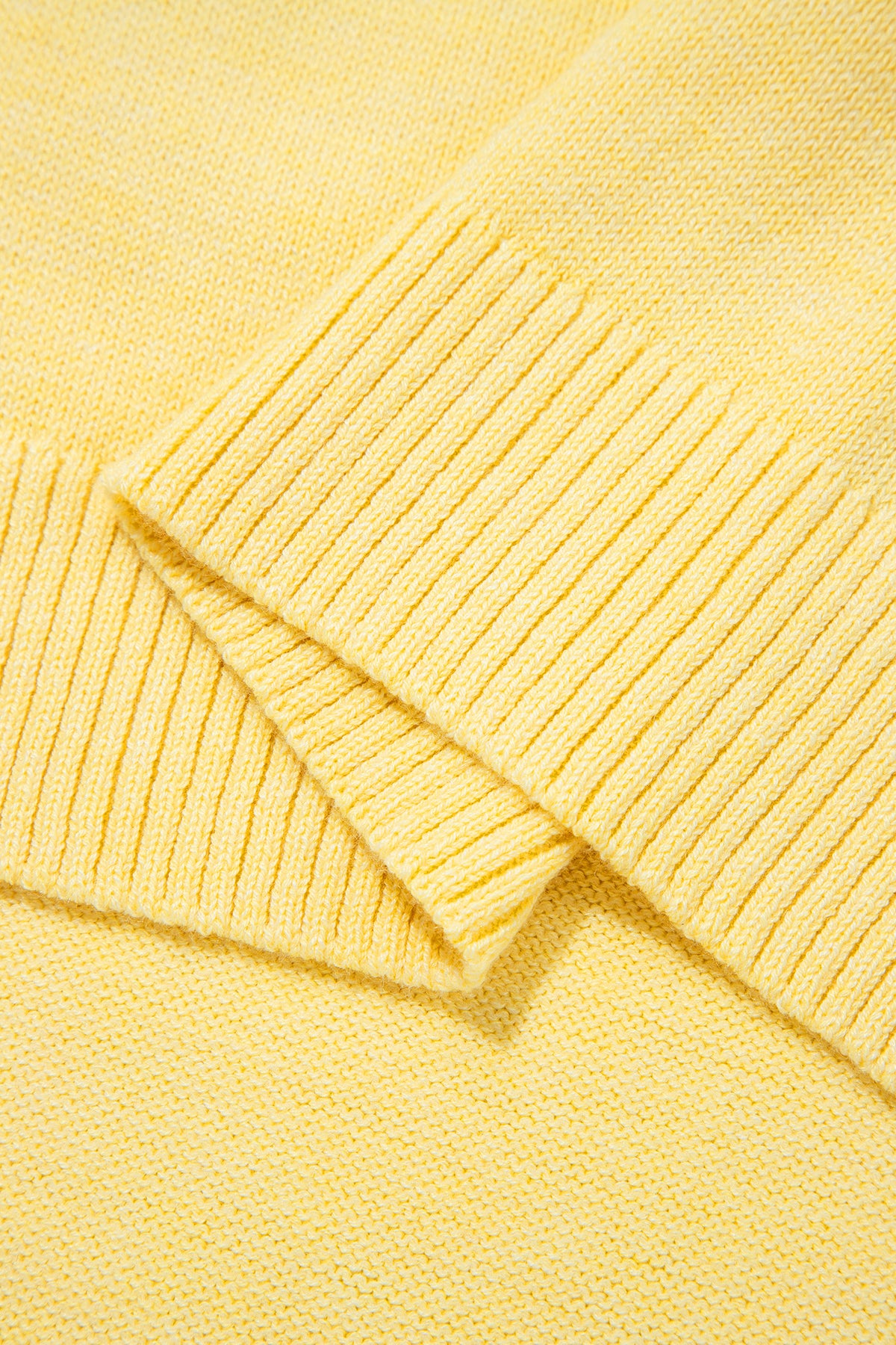 Détail maille du haut sans manches jaune, texture côtelée et ourlet.